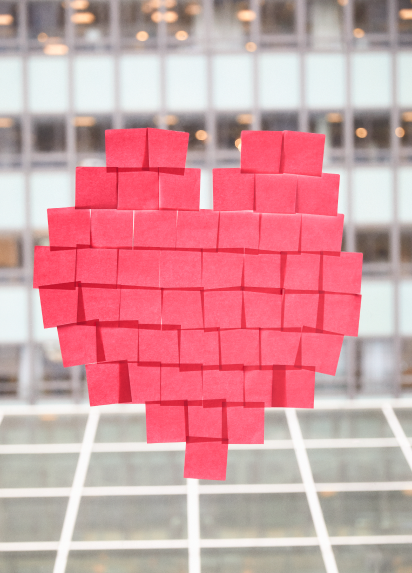 Pink post it notes arranged into a love heart on a window