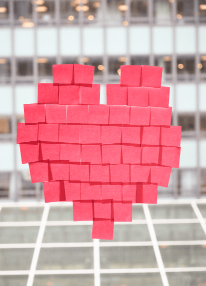 Pink post it notes stuck on an office window in the shape of a heart