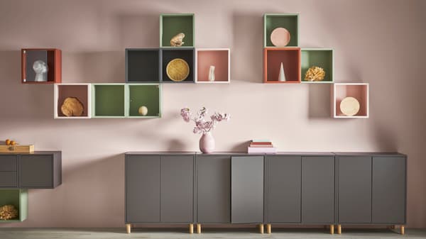 Planificador EKET color gris oscuro con florero rosado encima, gabinetes de diferentes dolores en la pared con accesorios en su interior.