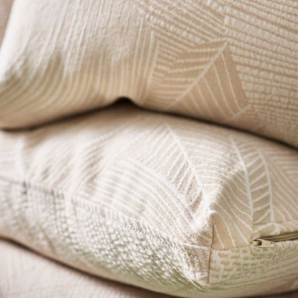 Plano detalle de cojines con la funda JÄTTEGRAN en tonos beige.