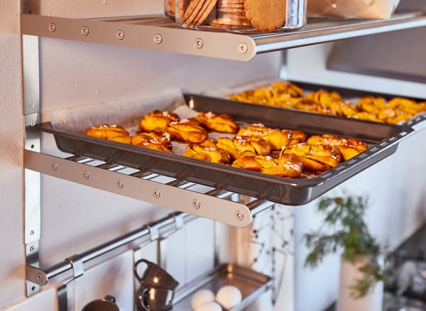 Plaques garnies de brioches tout juste sorties du four, posées sur une tablette en métal au-dessus du plan de travail.