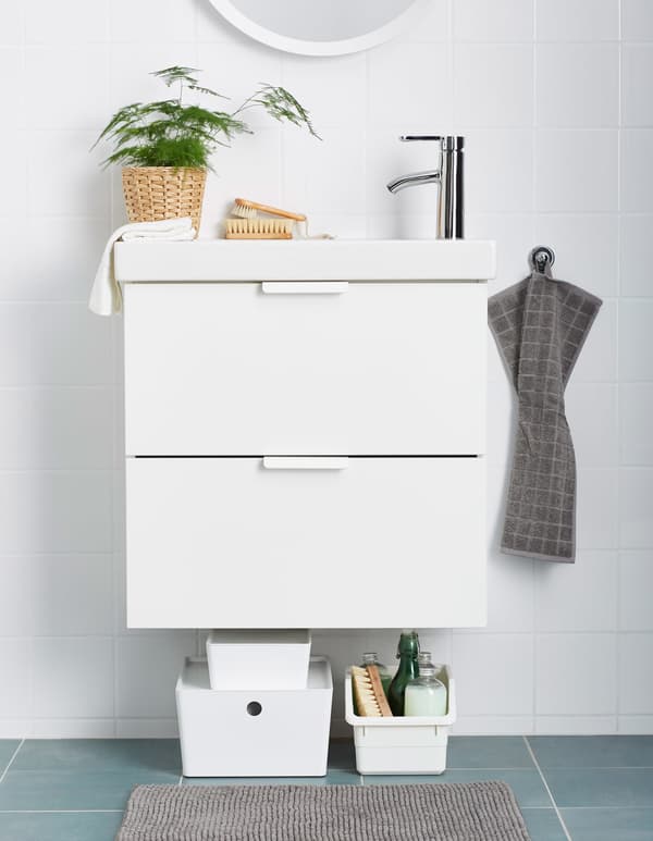 Plastic boxes holding cleaning supplies and sitting beneath a bathroom sink.