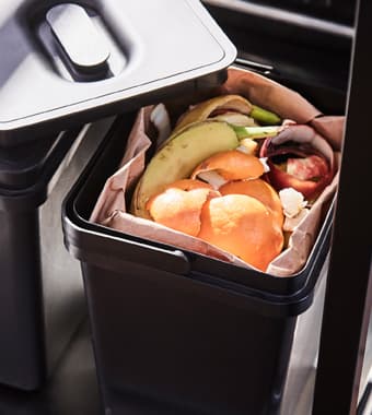 Plastikowy pojemnik na kompost stojący na najniższej półce wózka.