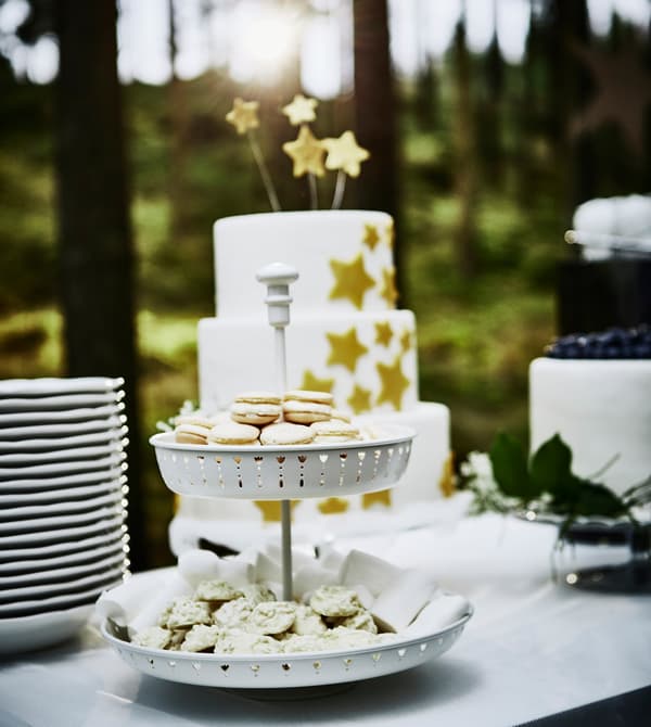 Plat à étages blanc rempli de petits biscuits sur une table à gâteau de mariage 