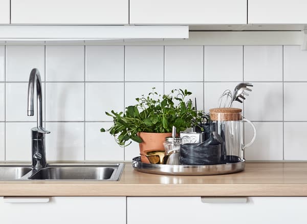 Plateau rond, déposé sur le comptoir, contenant des fines herbes, des articles de cuisine et une carafe