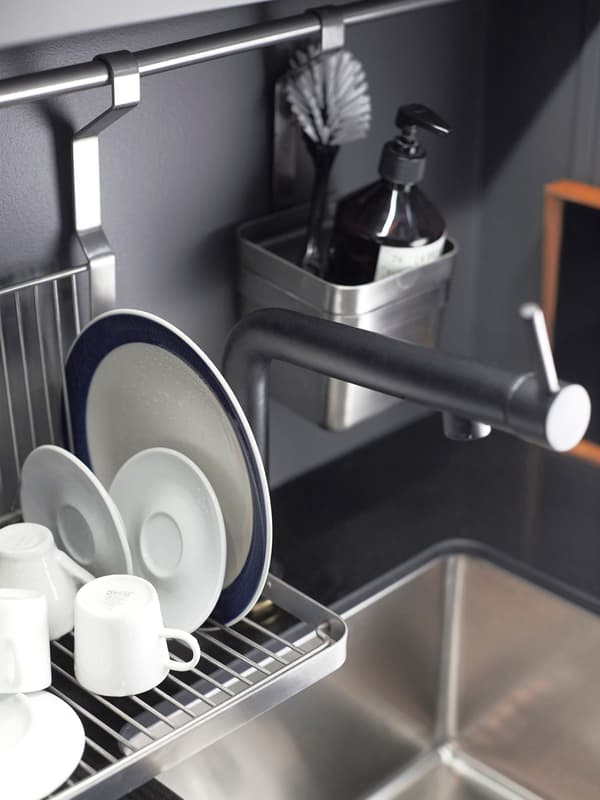 Plats, tasses i una safata s'eixuguen en un escorredor penjat al costat de l’aigüera de la cuina.