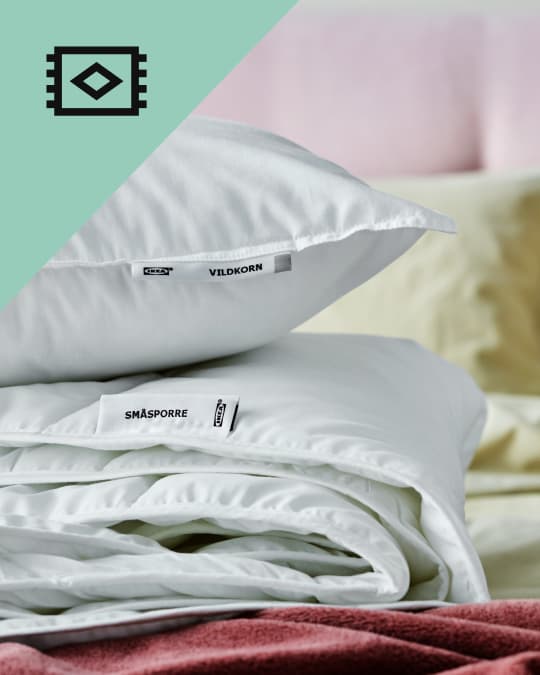 plumones blancos IKEA doblados sobre la cama.
