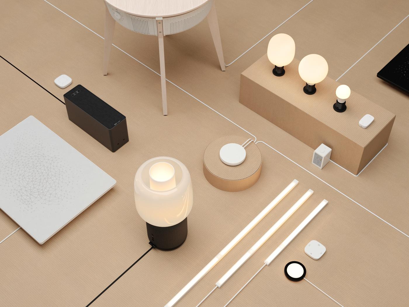 Plusieurs ampoules et produits SYMFONISK sont placés sur un fond beige, avec leurs cordons soigneusement tendus et organisés.