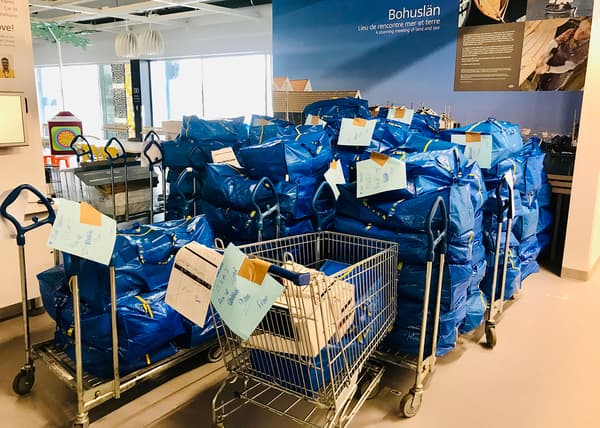Plusieurs chariots avec de grandes piles de sacs bleus IKEA remplis de fournitures.