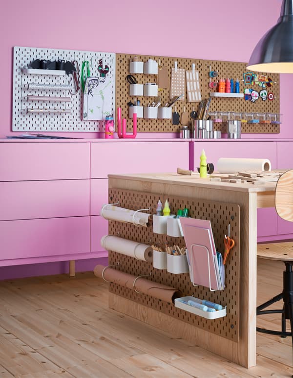 Plusieurs panneaux perforés SKÅDIS dans un coin bricolage, avec accessoires pour les fournitures, le papier et autres. 