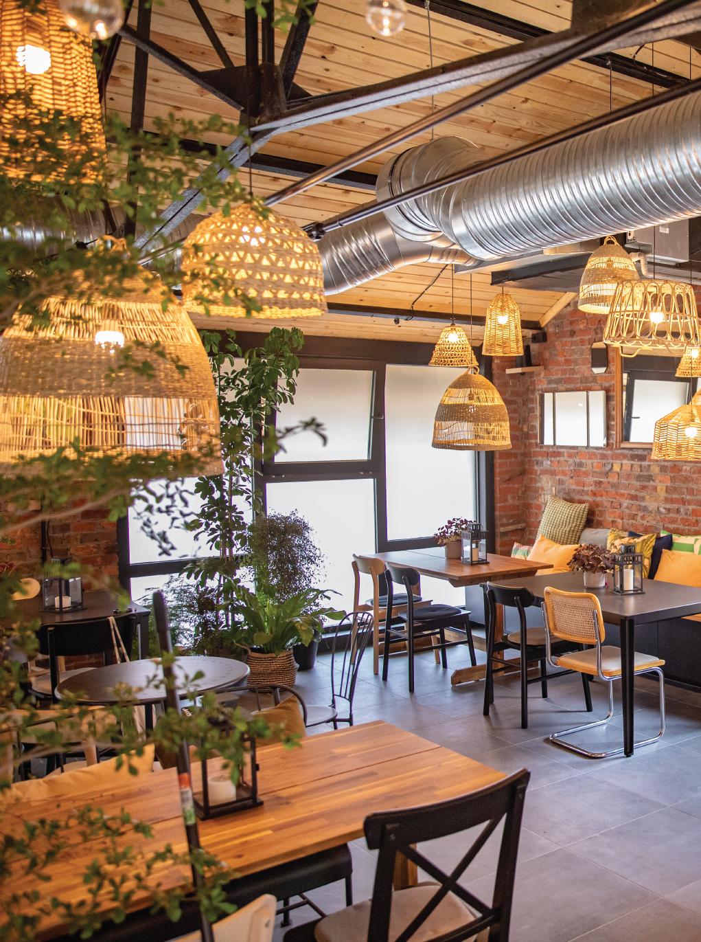 Plusieurs suspensions en matériau naturel dans une salle de restaurant avec des tables de 4 personnes.