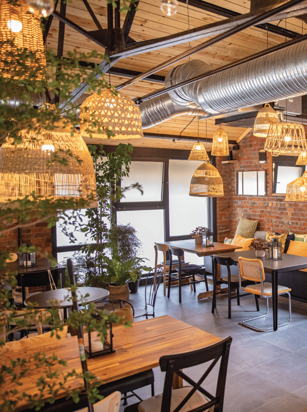 Plusieurs suspensions en matériau naturel dans une salle de restaurant avec des tables de 4 personnes.