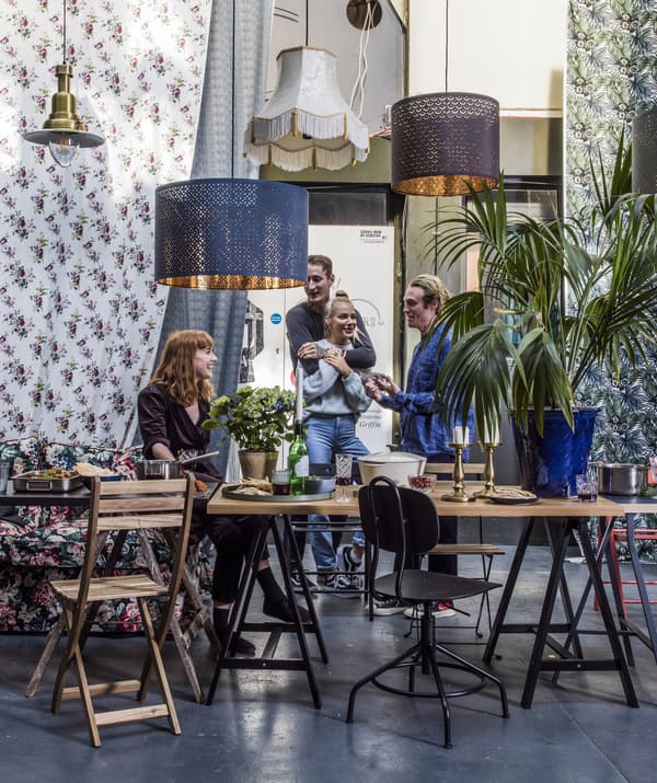 Plusieurs tables et chaises de salle à manger avec des personnes en pleine discussion et des suspensions accrochées au plafond.