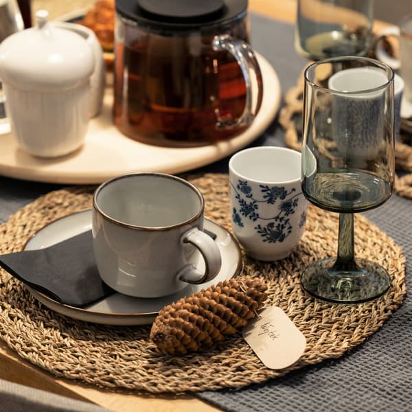 Podkładka pod talerz z kubkiem GLADELIG, kieliszkiem OMBONAD i szyszką.