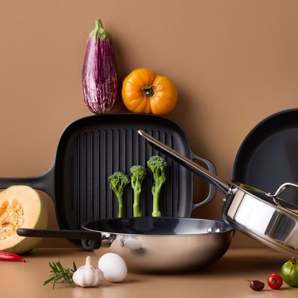 Poêles à frire et légumes à cuire sur un fond beige