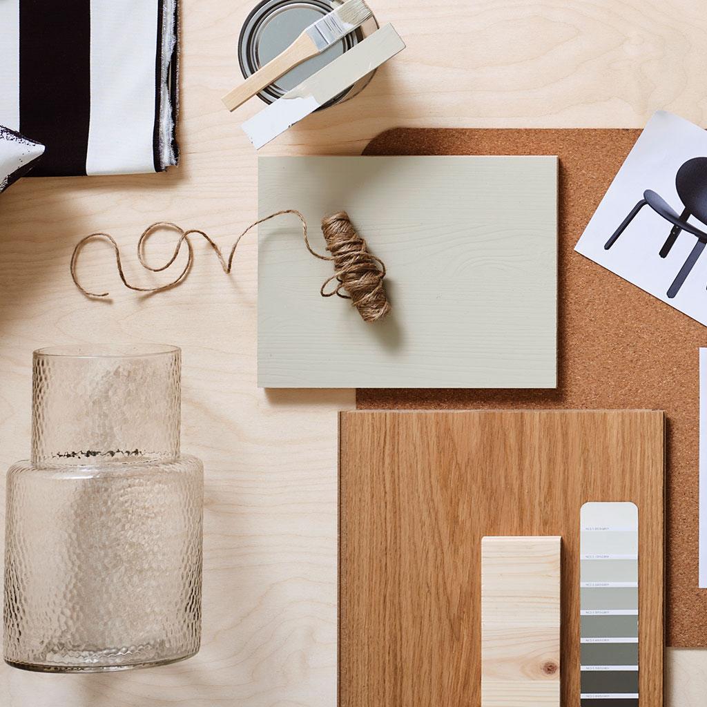 Pöydälle koottu värikarttoja, tuotekuvia ja maalipurkki + suti.