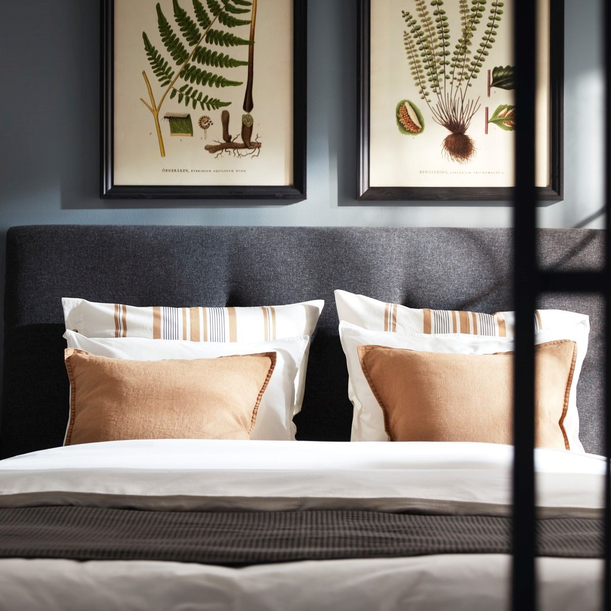 Pohľad na elegantne prestretú posteľ, nad ktorou sú obrazy.