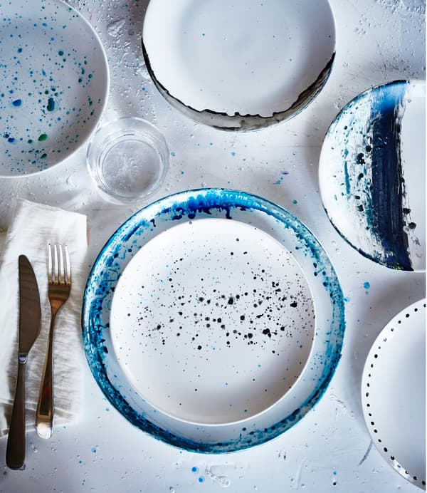 Pohľad zhora na biele taniere IKEA FÄRGRIK s rôznymi vzormi v odtieňoch modrej.