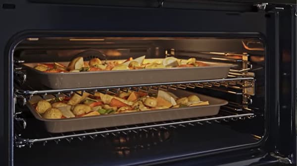 Pohled zblízka na mikrovlnnou troubu s pokrmy na dvou roštech uvnitř.