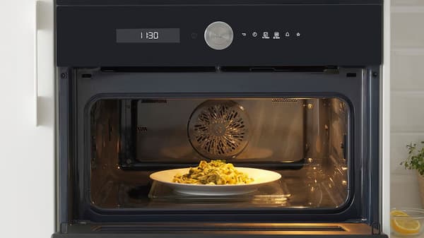 Pohled zblízka na rozsvícenou mikrovlnnou troubu s pokrmem uvnitř.