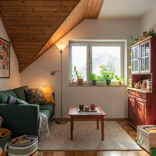 Pokój dzienny z zieloną sofą, stolikiem kawowym i lampą FLUGBO. 