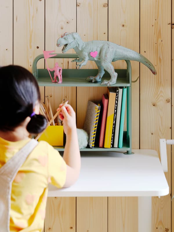 Policový díl na stůl RELATERA, na horní poličce stojí dinosaurus.