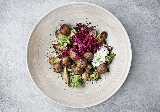 Polpette vegetariane con cavoletti di Bruxelles e cavolo rosso sottaceto, servite su un piatto in legno – IKEA