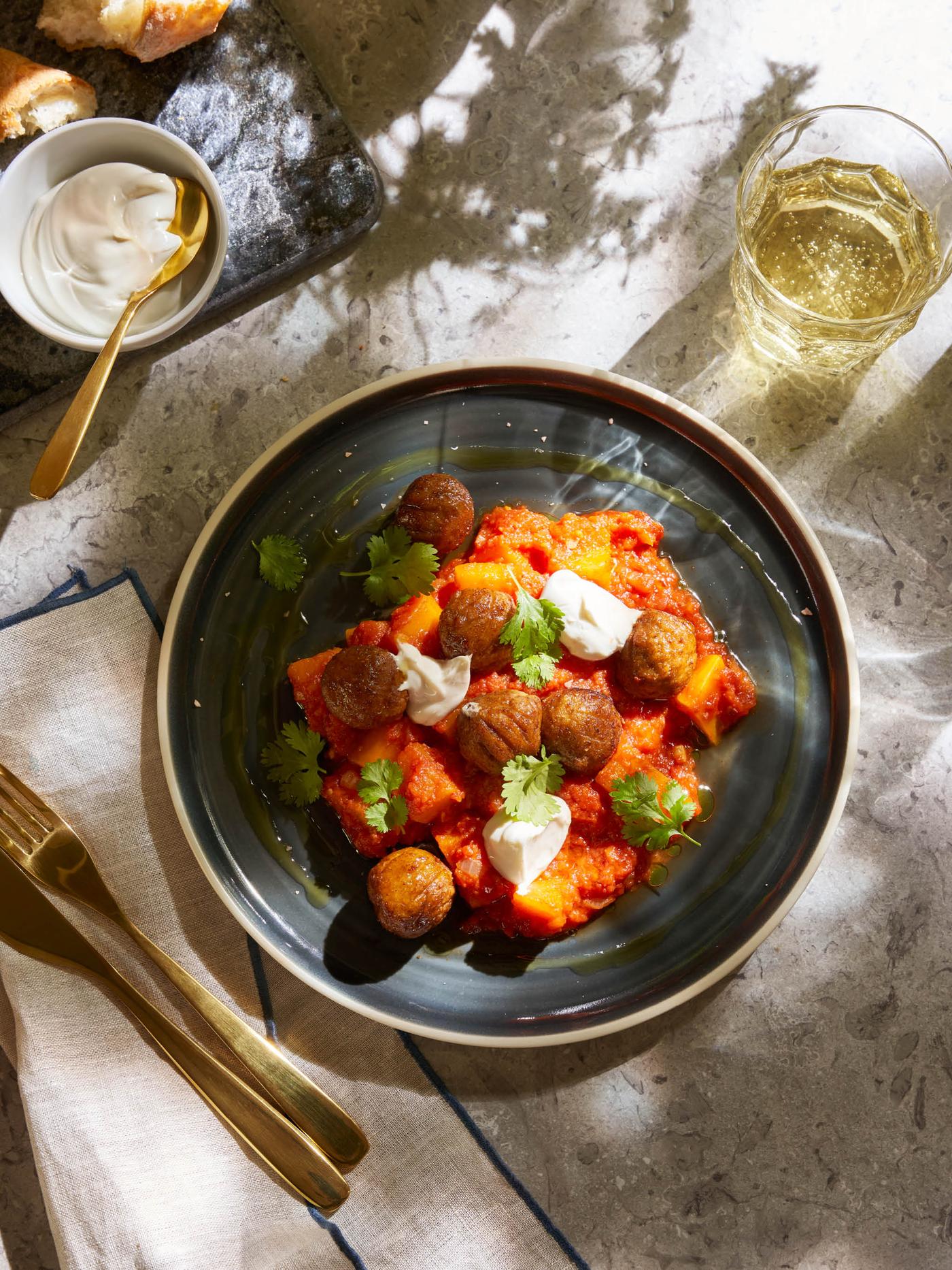 Porce dýôvo-rajčatového krému s bezmasými kuličkamu HUVUDROLL na tmavě šedém talíři OMBONAD.