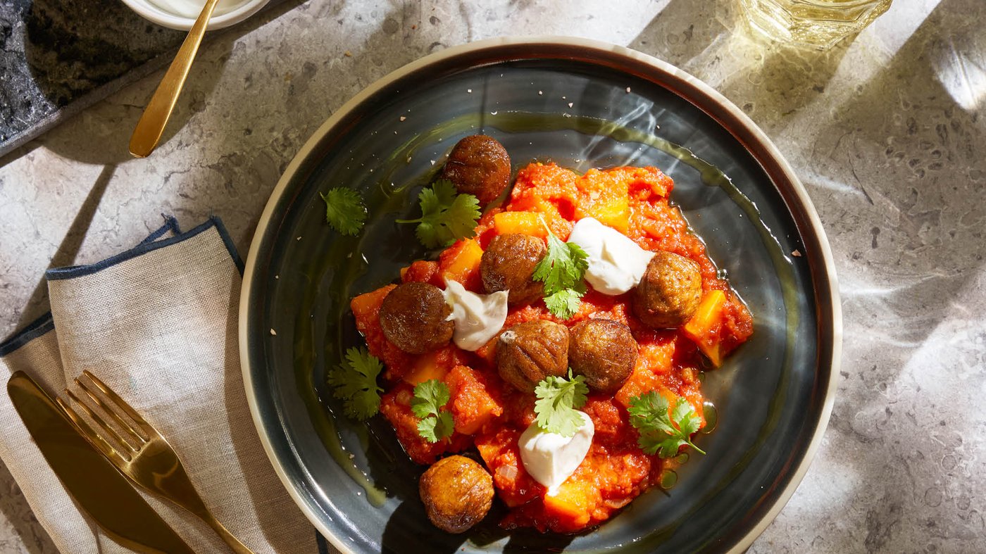 Porcia tekvicovo-paradajkového krému s bezmäsitými guľôčkami HUVUDROLL na tmavosivom tanieri OMBONAD.