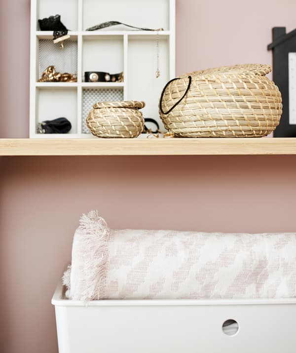 Pormenor de pequenos cestos e caixas de arrumação em cima de prateleiras.