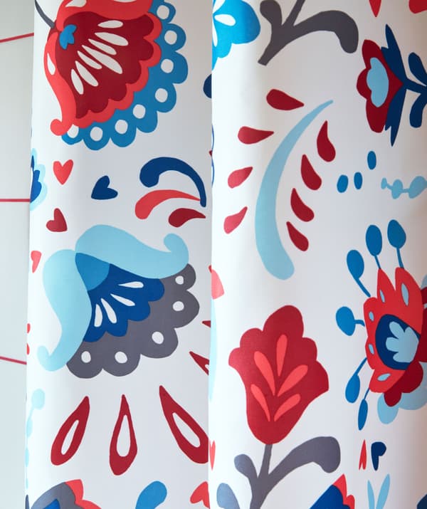 Pormenor de uma cortina de duche, em cores vivas e decorada com um padrão sueco tradicional com cornucópias.