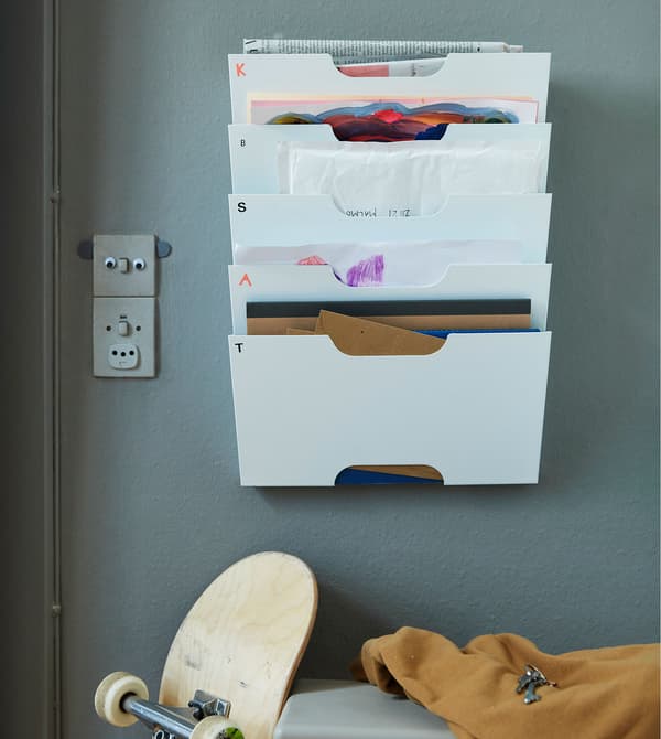 Portariviste da parete KVISSLE bianco, pieno di documenti vari e appeso a una parete grigio-verde - IKEA
