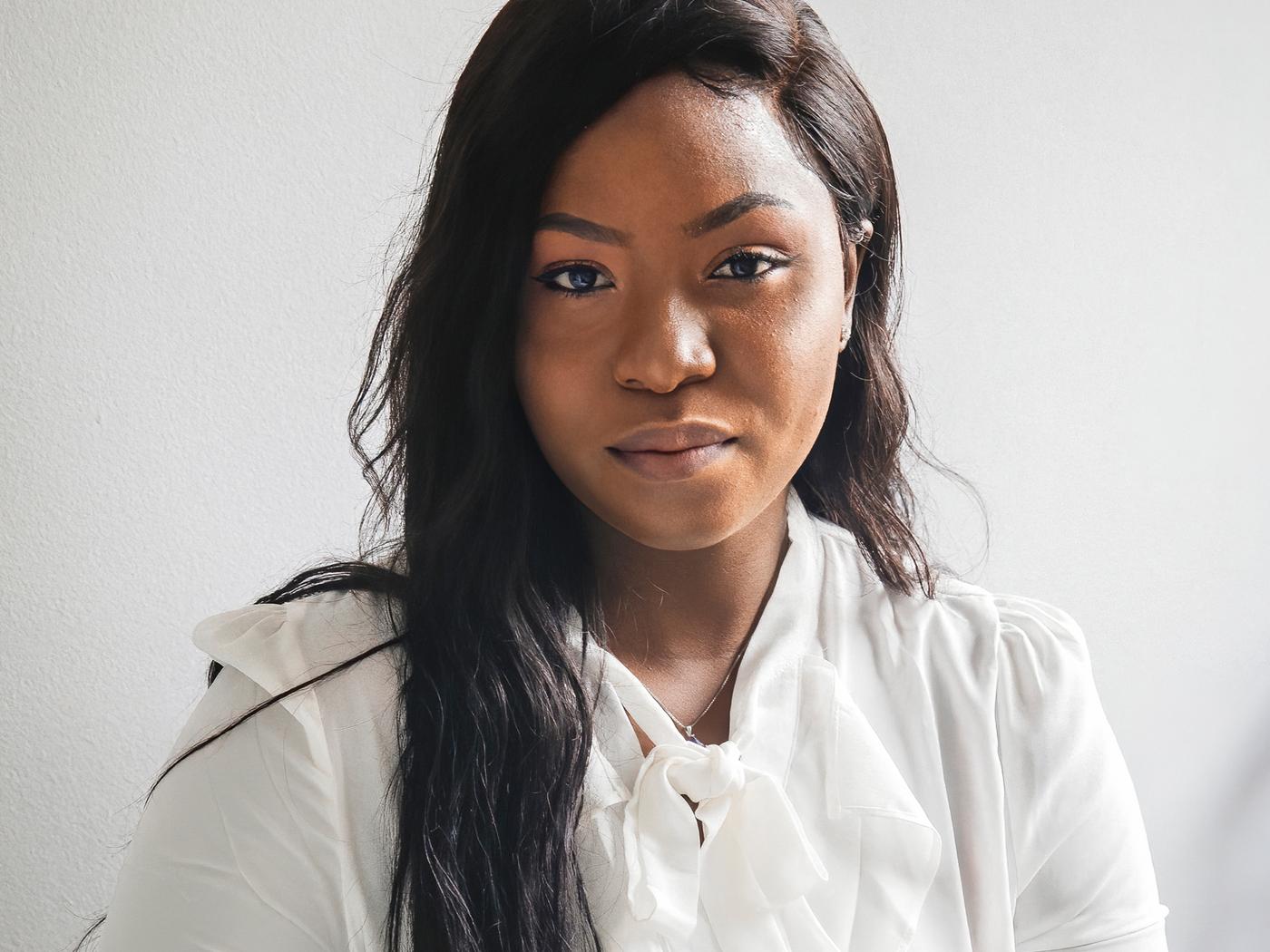 Porträtt av Precious, en flykting från Nigeria och medarbetare på IKEA Kanada som bär en vit blus.