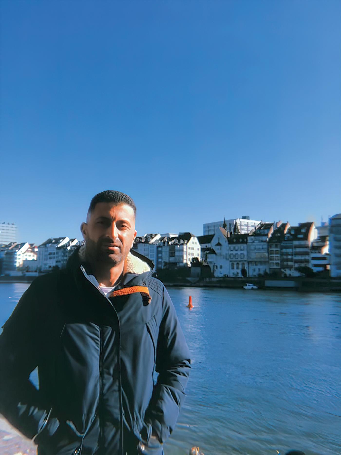 Portrait d’Odai, réfugié irakien et collaborateur IKEA Suisse, debout devant une rivière.