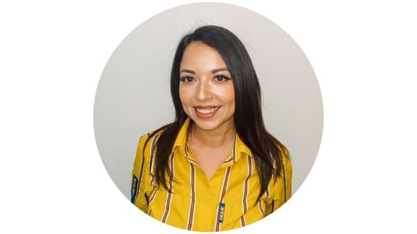 Portrait en gros plan d’une personne souriante portant une chemise jaune à rayures, sur fond clair.
