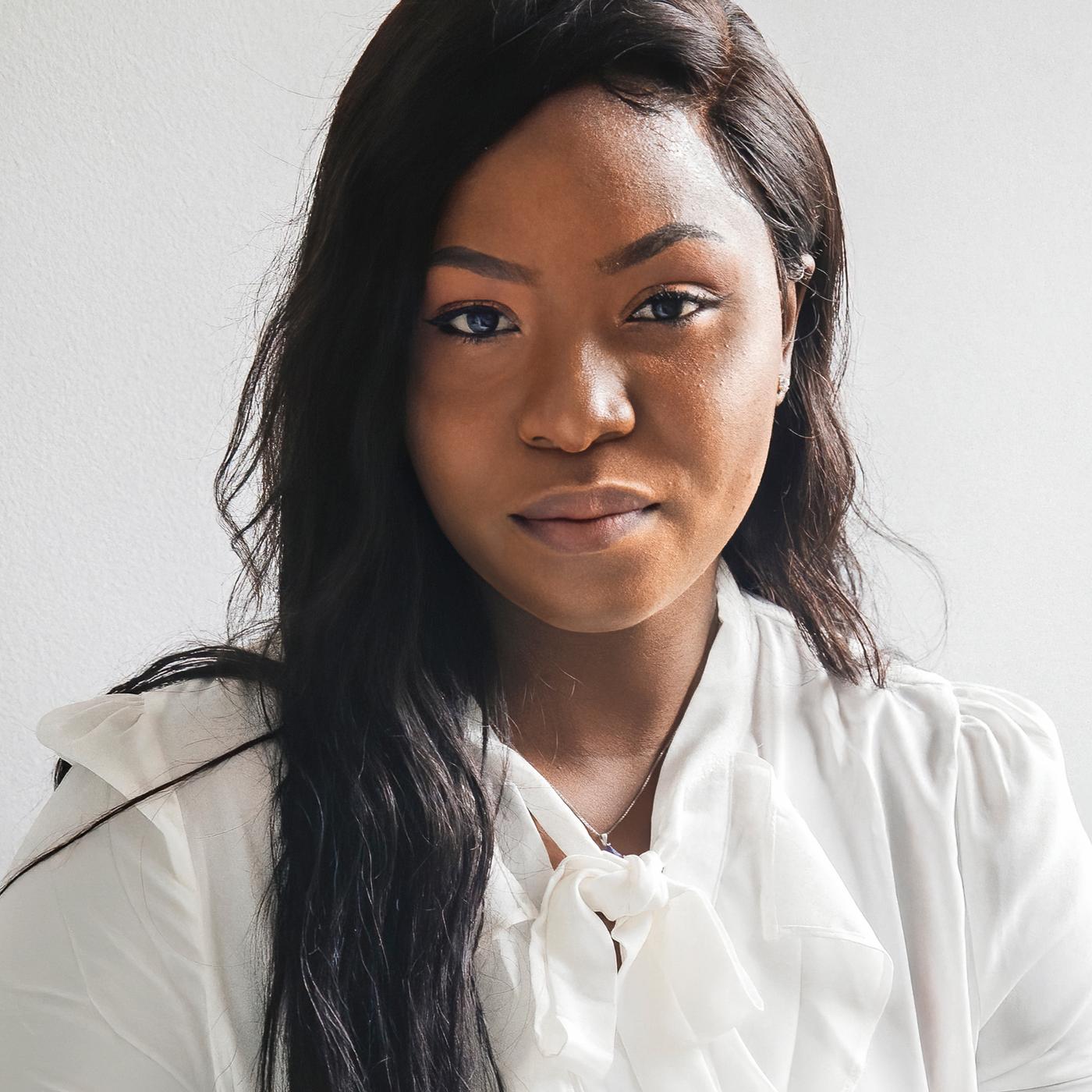 Portrait of Precious, a Nigerian refugee and IKEA Canada co-worker, wearing a white blouse.