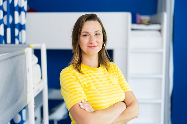 Portrait of smiling woman in yellow striped shirt standing in children’s room with bunk bed