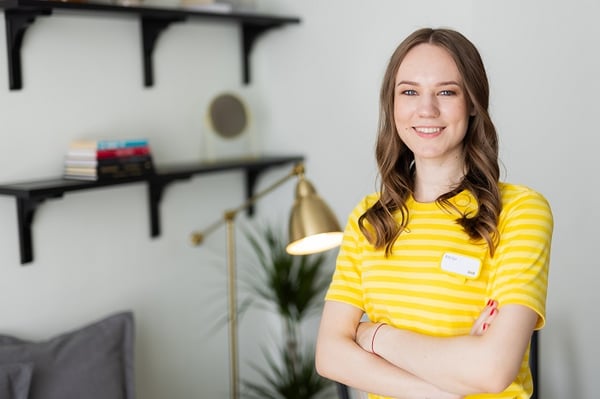Portrait of smiling woman in yellow striped shirt standing in modern living room interior