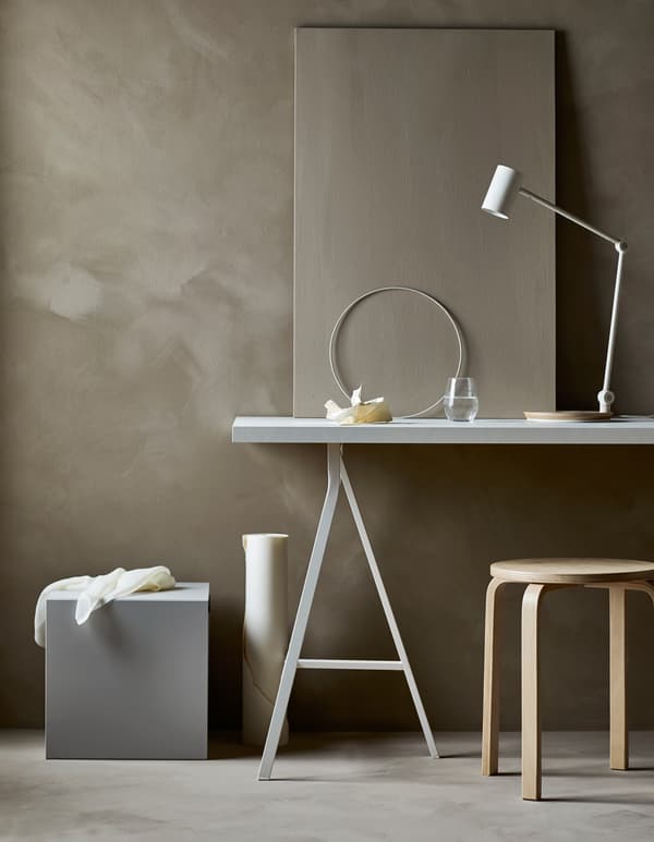 Poste de travail dans un séjour minimaliste, avec bureau, fauteuil et fournitures cachées dans un cube de rangement