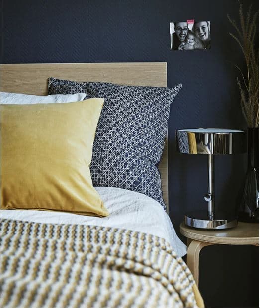 Postel, noční stolek, lampa, tmavě modrá stěna