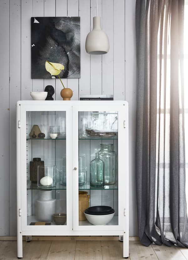 Poteries et verres dans une vitrine blanche.