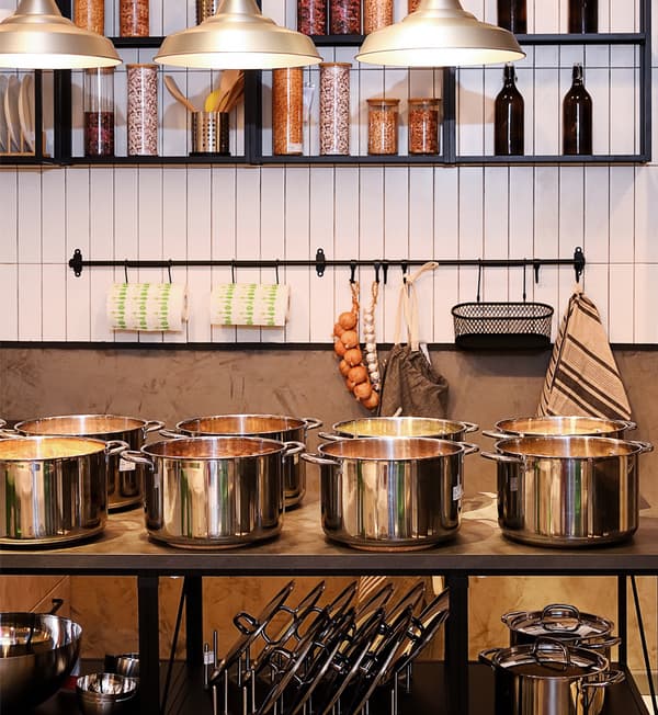 Pots and lids of different sizes are displayed on a countertop with storage.