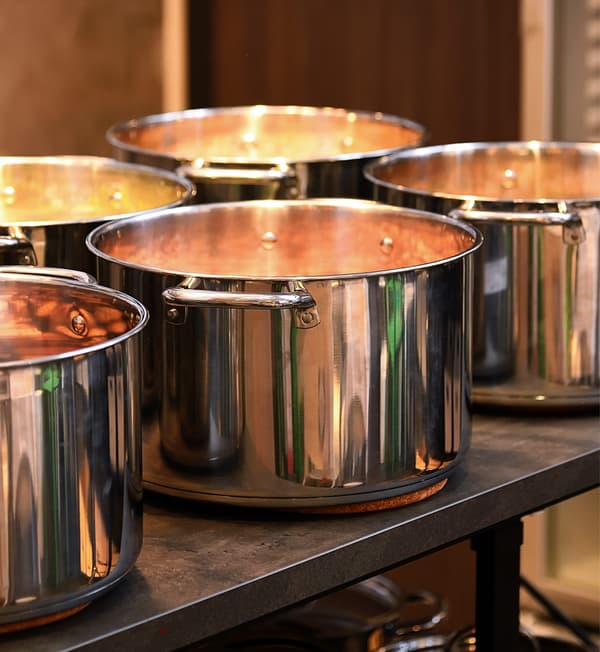 Pots of various soups are placed on top of grey countertop.