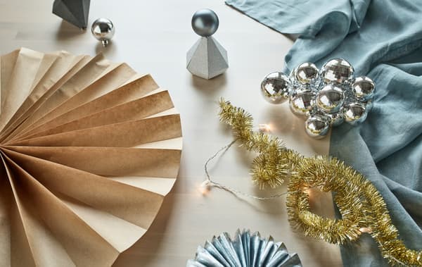 Pour tes décorations, tu peux recycler les accessoires de fêtes IKEA tels que les guirlandes dorées VINTER 2017, les boîtes cadeaux argentées, les boules et le papier d’emballage. Transforme-les en décorations murales, décorations de table et rosaces en papier.