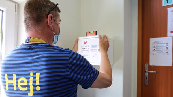 Pracownik IKEA montuje na ścianie szafkę z bezpłatnymi artykułami higienicznymi dla kobiet