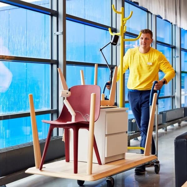 Pracownik IKEA prowadzący wózek pełny zakupów z działu Okazji na Okrągło.