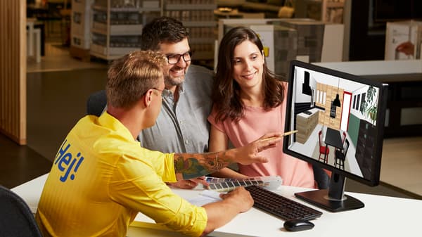 Pracownik projektuje wnętrze. Obok siędzą obserwujący go glięci