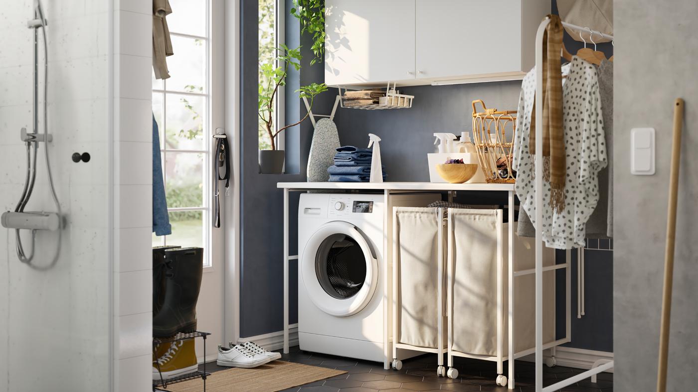 Praonica plavih zidova s bijelom ENHET kombinacijom za odlaganje, perilicom rublja i dvije košare za rublje na kotačima.