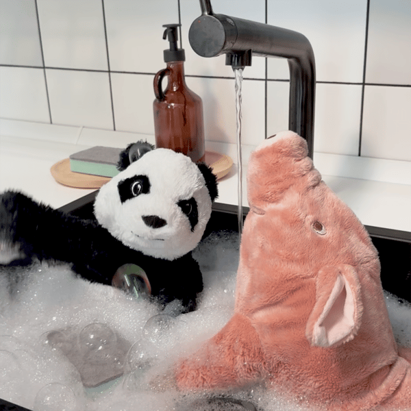Prasiatko a panda, plyšové hračky, sa spolu kúpu v umývadle.