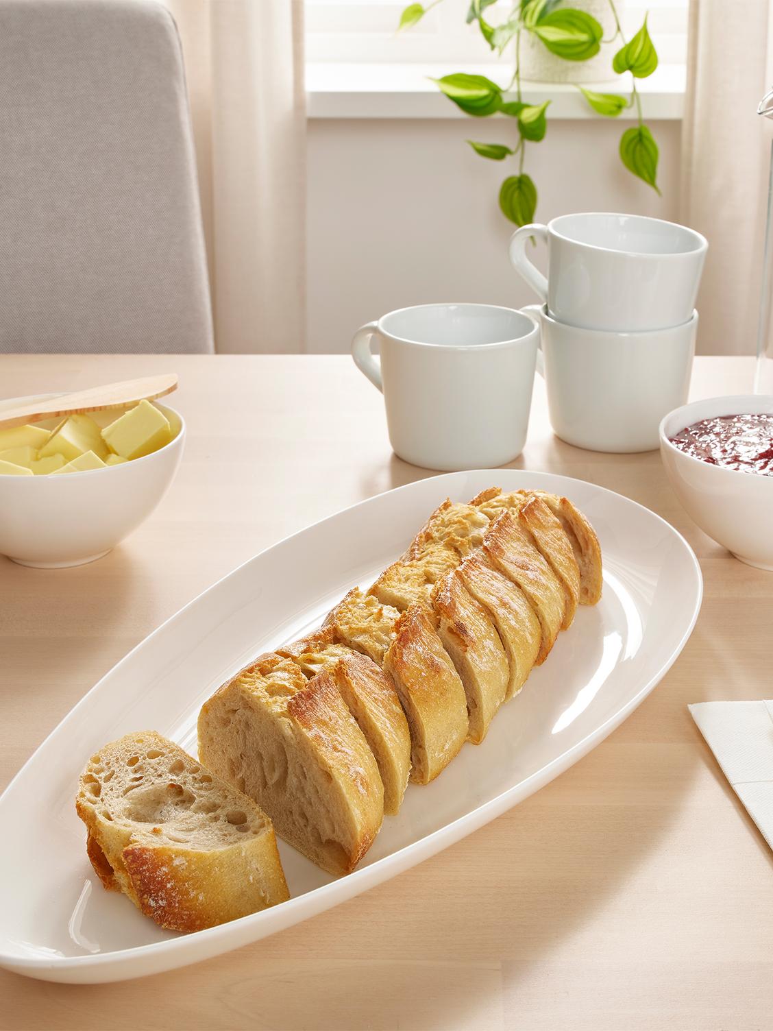 Pratos e tigelas em branco, de vários tamanhos, empilhados uns sobre os outros, ao lado de um copo.